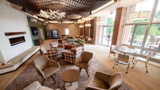 Lounge in Lee Hall with a mix of armchairs, plaid seating, round tables, vending machines, and large windows overlooking the outdoor patio.