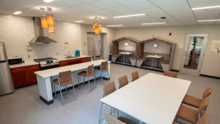 Community kitchen and study area with modern appliances, bar seating, a large table, and two booth-style study nooks.