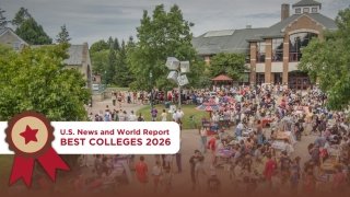 A Large crowd of students and community members gathered outdoors at St. Lawrence University’s campus, surrounded by trees and academic buildings. Booths and tables line the walkway during a vibrant campus event. A U.S. News and World Report “Best Colleges 2026” badge is displayed in the foreground of the image.