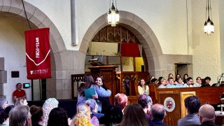 A student hugs their professor during an awards ceremony in the campus chapel.