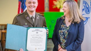 Cadet Cole Siebels ’26 holds up a document officially commissioning him as an officer in the Army.