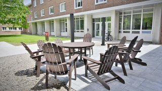 Brown outdoor chairs and table setup in a common patio of the newly renovated Whitman Hall.