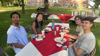 College students sitting at outdoor dining table with food