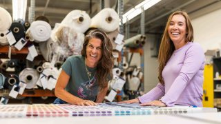 Carey Scully Strobeck and her creative partner laugh while looking at fabric samples.
