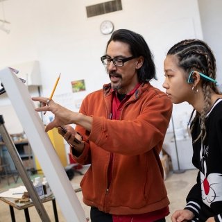 Faculty member working with student on painting