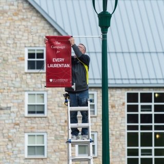 Man hanging sign on campus
