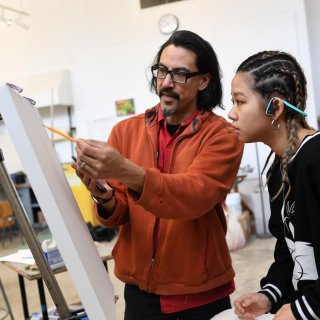 A student collaborates with her professor as she begins the sketch for a painting.