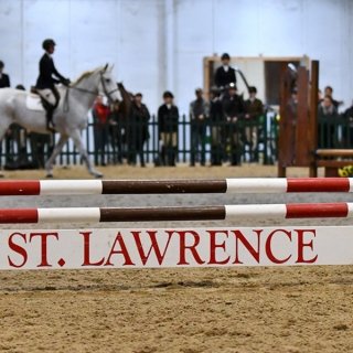 A jump with &quot;St. Lawrence&quot; on it and a horses and riders behind it