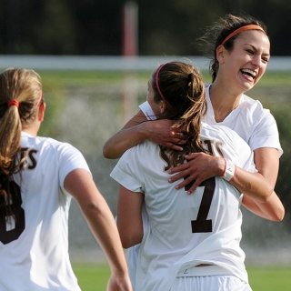 Three soccer players celebrate