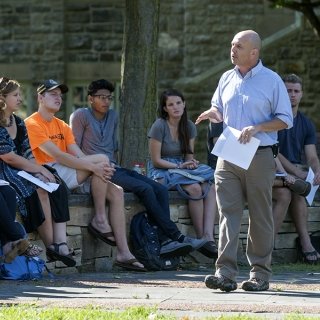 Professor stands in front of students in an outdoor classroom.