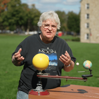 Aileen O'Donoghue, wearing a black T-shirt that reads, &quot;advice from the moon,&quot; stands on the Kirk Douglass quad in front of a solar system replica and explains what people can expect during the next total solar eclipse.