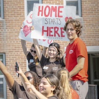 Group of OL cheering, holding &quot;Welcome Home&quot; sign