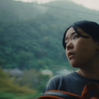 Film still from Chronicle of a City showing a woman looking out a train window