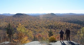 A view from the peak of a mountain overlooking fall foliage in the Adirondacks.