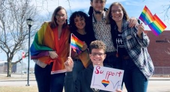 A group of five Saint Lawrence students holding rainbow flags at the Potsdam Pride March.