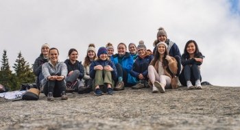 Twelve Saint Lawrence students sit on a rock at the summit of Balanced Rock, Lake Placid, New York.
