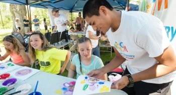 A Saint Lawrence University student works with school children on a finger painting project.