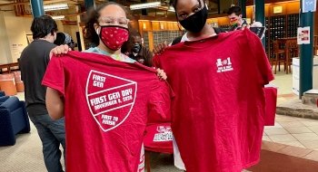 Two Saint Lawrence University students hold up t-shirts during National First Generation Celebration Day.