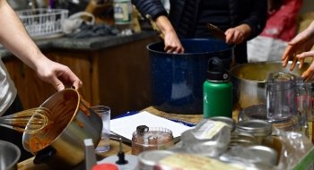 Students mixing dressing for kimchi in large pots at a kitchen table.