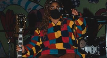 A Saint Lawrence student with their guitar on stage during an open mic night at the live music venue on campus.