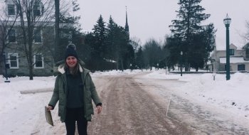 A prospective students stands on a snow-covered path on the Saint Lawrence University dorm room.