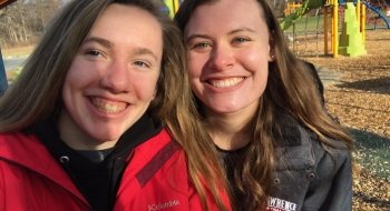 Two students stand next to each other and smile for a selfie.