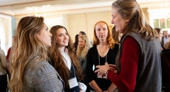 Three students gather around a Laurentian in conversation during a business casual networking event.