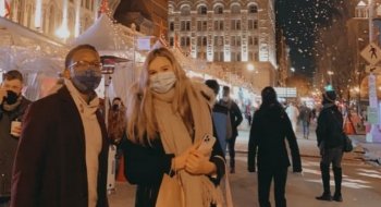 Two students standing at Union Market in Washington D.C. smiling for a photo while it snows behind them.