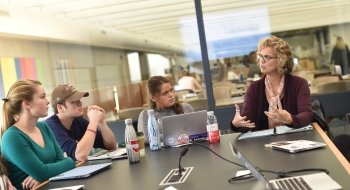 Professor Liz Regosin sits at the head of a discussion table, leading a conversation among her students.