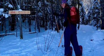 A young woman at the trailhead where she's cross-country skiing.