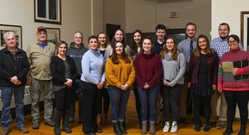 A group of 20 Saint Lawrence students stand with their professors as they receive an award.