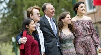 President Fox stands with four happy students looking off to the right for a photo.