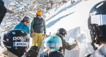 A group of students in ski gear dig a snow pit in five feet of snow. It's a bright, sunny day in Teton Pass.