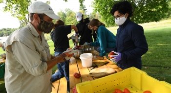 A professor guides a small group of students as they examine vegetables grown on our farm.