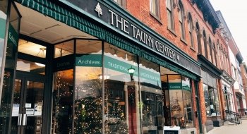 Looking up the street at brick buildings and storefronts, decorated for the holidays, on a Main Street in Canton, N.Y.