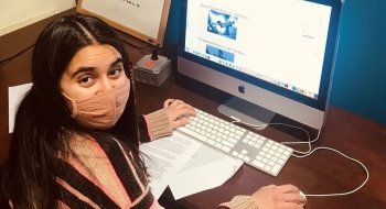 A student wearing a mask and preparing a layout on a computer.