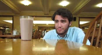 Jake Saint Pierre, sitting in a dining hall, looks at a glass of chocolate milk.