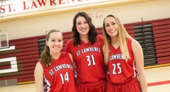 Kaelyn Kohlasch and two fellow members of the Saints women's basketball team, wearing red jerseys on the basketball court.
