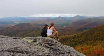 Two Saint Lawrence students sit on the summit of a mountain in the Adirondack Park.