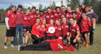 A group of Saint Lawrence ultimate frisbee players, wearing red jerseys, stand in a group.