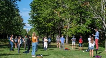 Associate Professor David Murphy teaches an outdoor class underneath a large row of green trees.