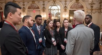 Several Saint Lawrence students, wearing professional attire, speak with an alumni during a networking event in Washington, D.C.