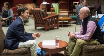 A Saint Lawrence University student, wearing professional attire, partakes in a mock interview with a Saint Lawrence University alumnus.