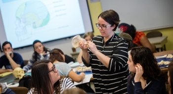 Minde Pitre, in a classroom of Saint Lawrence University students, examines skeletal remains.