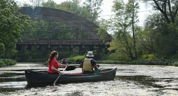 Two Saint Lawrence students navigate a river near campus in a canoe.