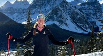 Lucy Hochschartner '20 wearing Nordic ski apparel and standing on a snowy peak overlooking the Canadian Rocky Mountains.