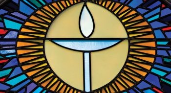 A photo of a stained glass window found in Atwood Hall Chapel of a single candle.