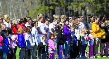 A photo of women's lacrosse players lined up with young community members.