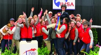 A photo of the equestrian team huddled together celebrating.