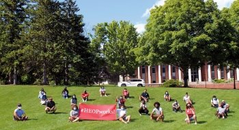 Students sitting on the grass with HEOP sign